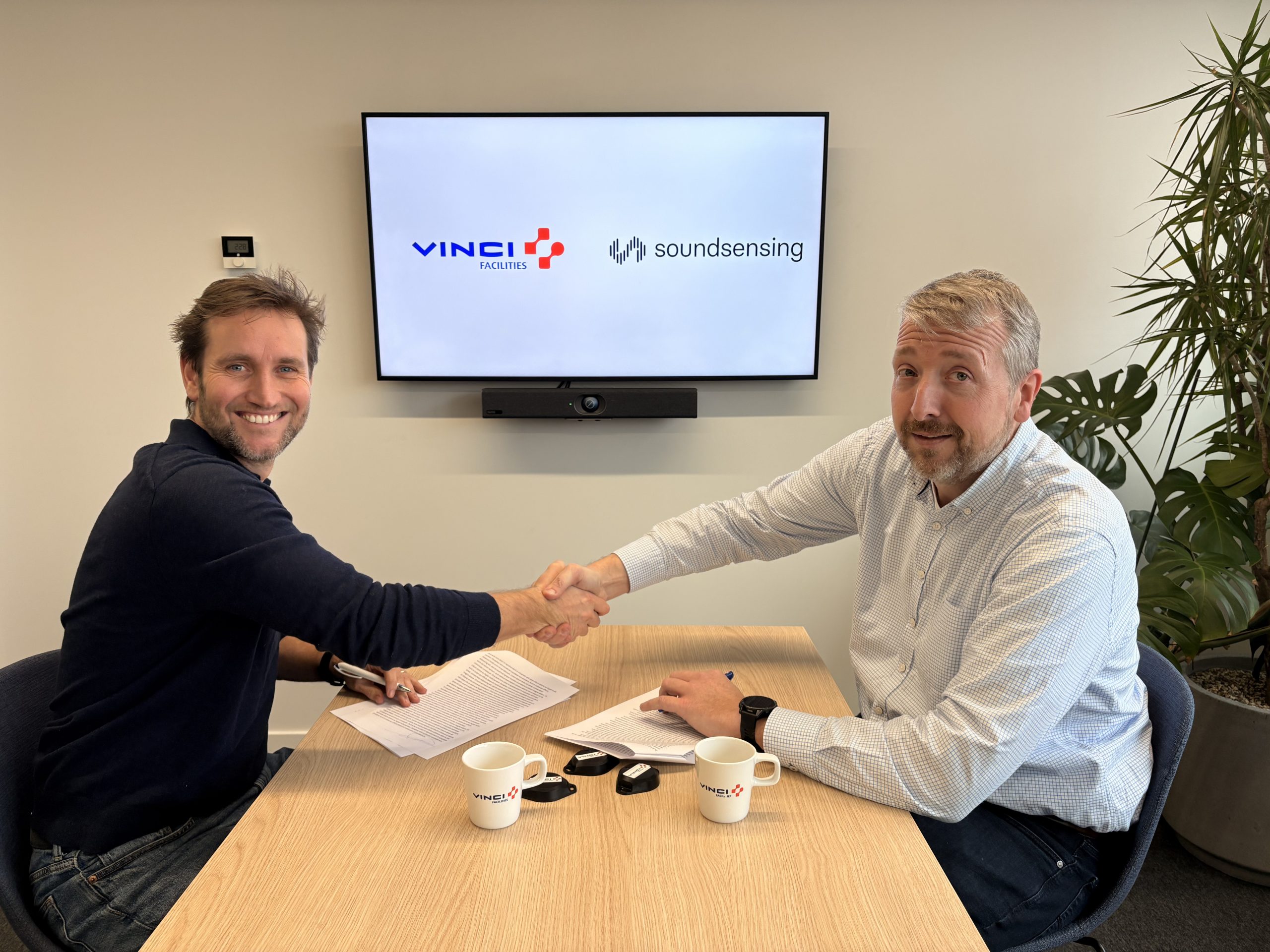 Ward Beniest and Tom Van Coillie signing a partnership agreement between VINCI Facilities and Soundsensing in a meeting room